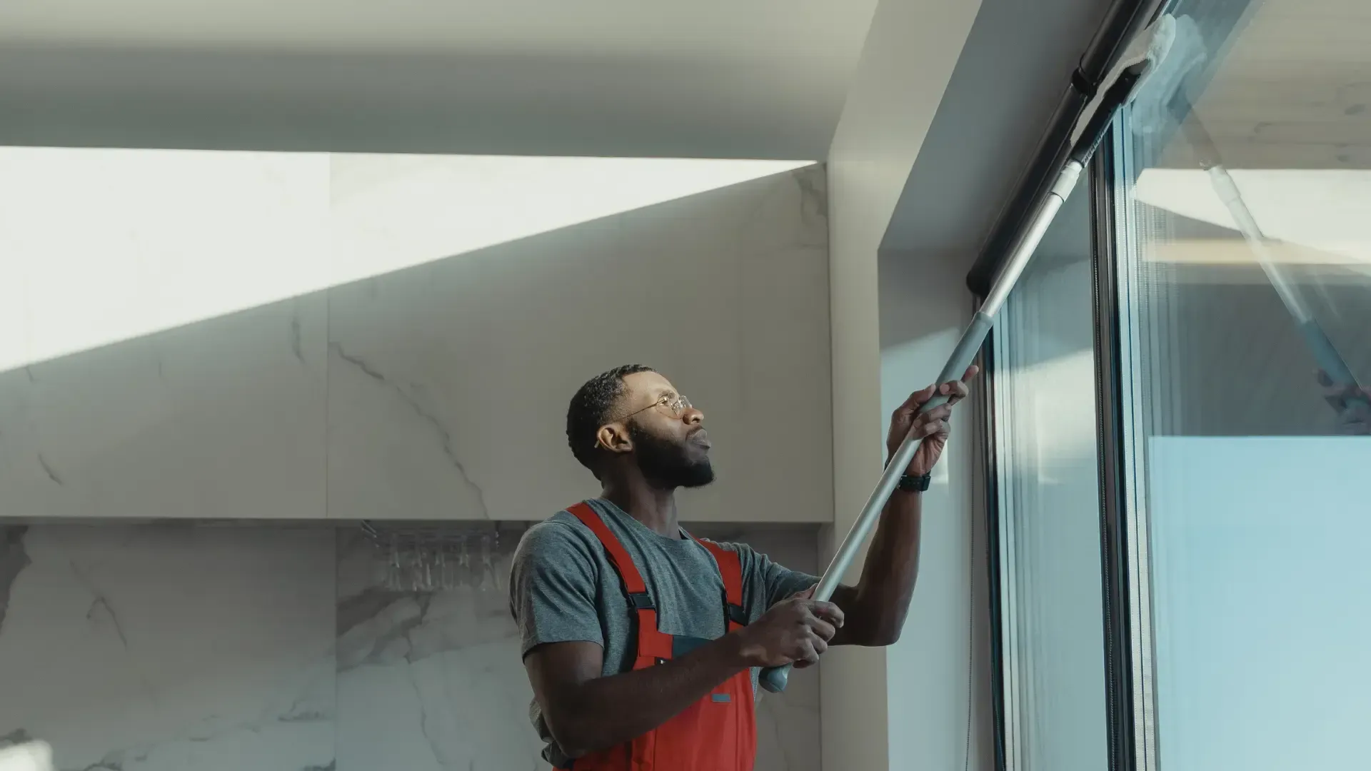 a man is cleaning a window with a mop .