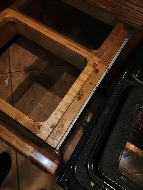 a stove top oven with a wooden drawer underneath it .