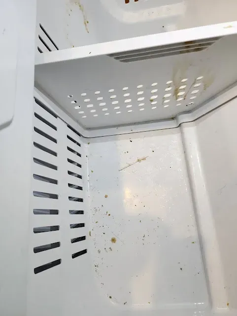 the inside of a dirty refrigerator with holes in it