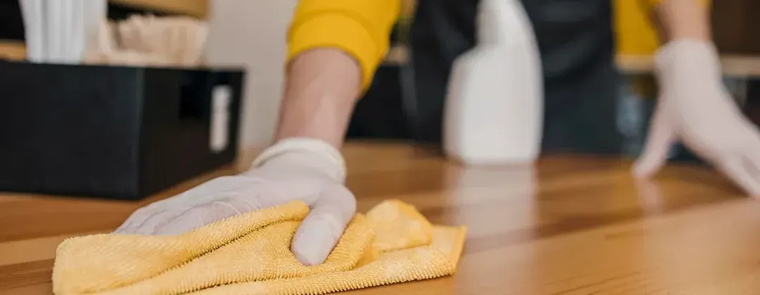 A person is cleaning a wooden floor with a cloth.