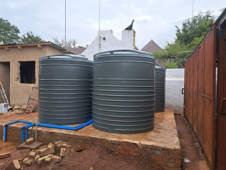 A group of water tanks are sitting next to each other in a yard.