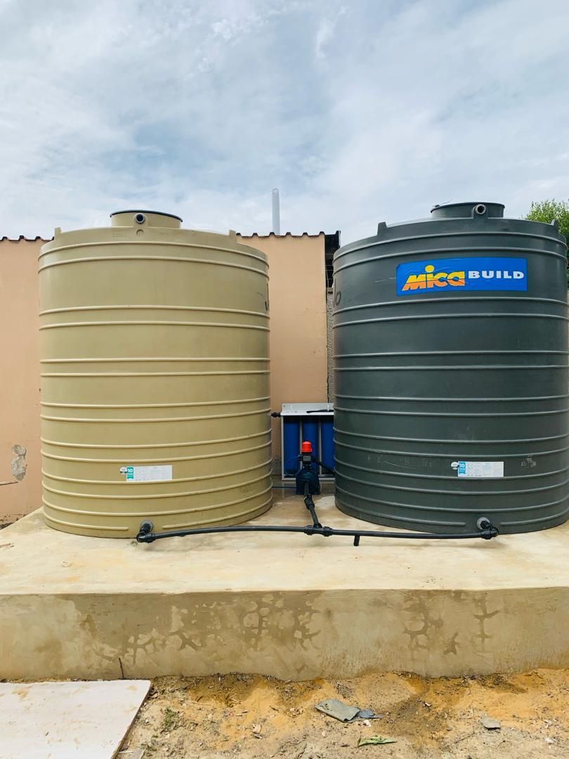 Two water tanks are sitting next to each other on a concrete platform.