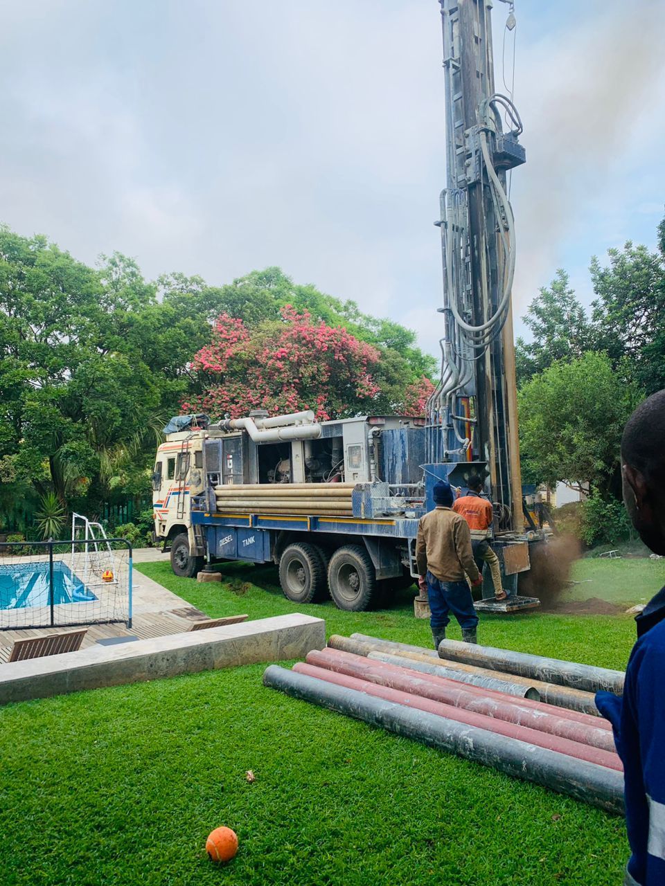 A man is standing in front of a truck that is drilling a hole in the ground.