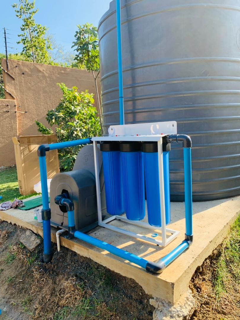 A blue water filter is sitting next to a water tank.