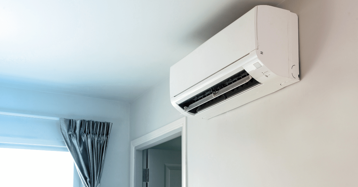 A white air conditioner is hanging on a white wall in a room.