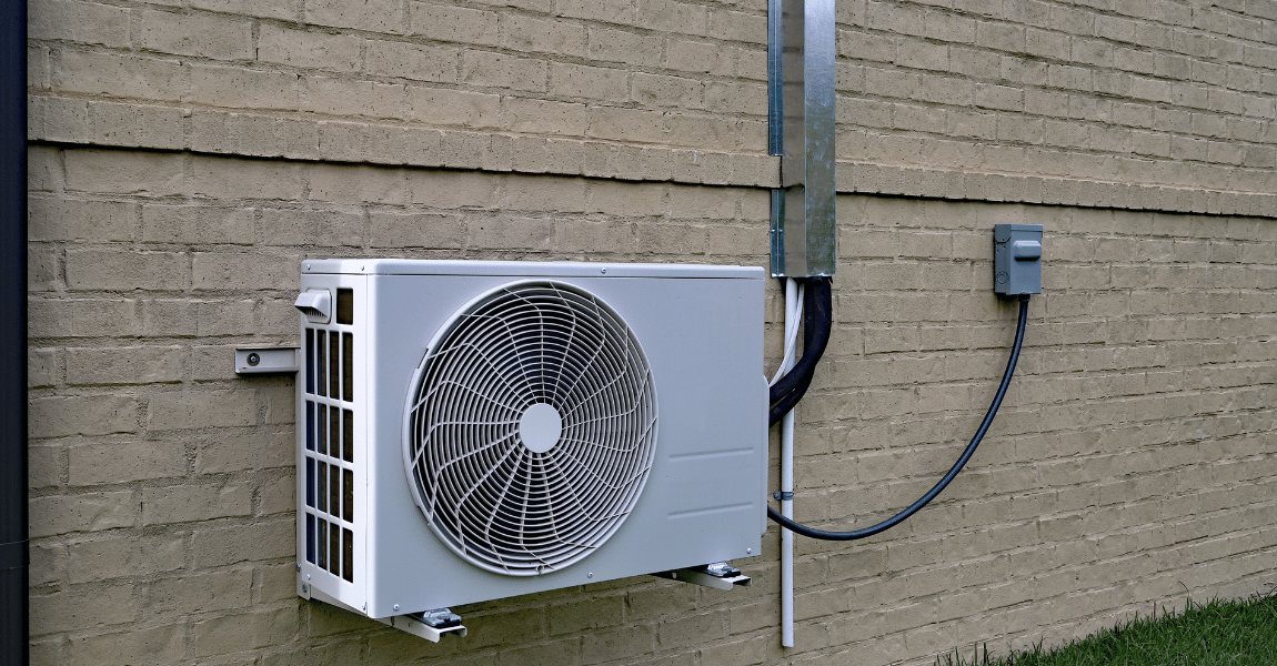 A white air conditioner is mounted on the side of a brick building.