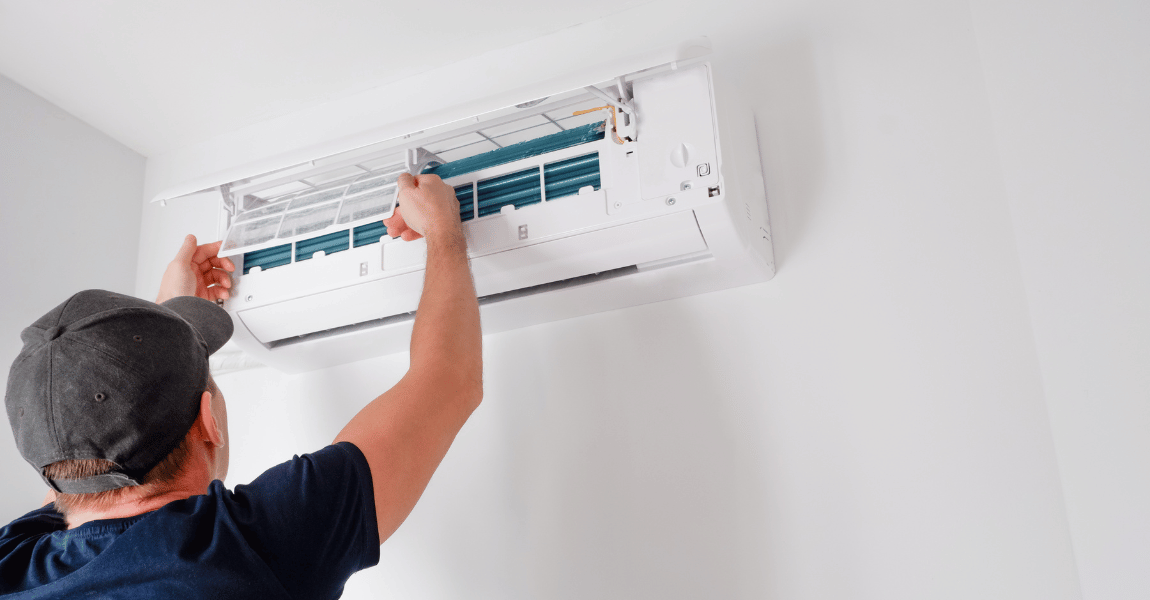 A man is installing an air conditioner on a wall.