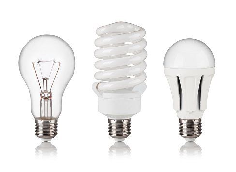 Three different types of light bulbs are sitting next to each other on a white background.