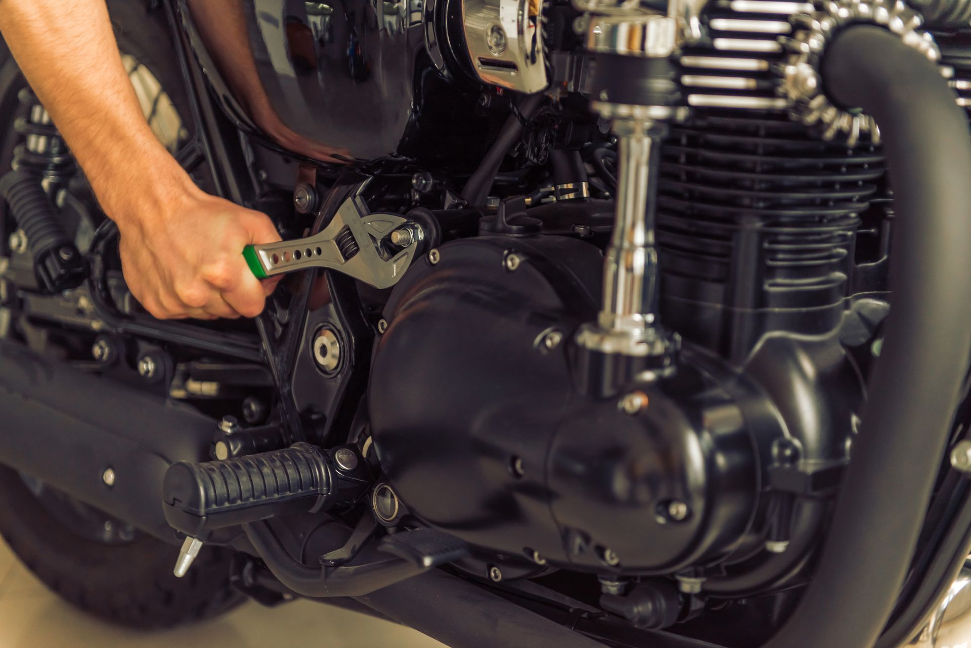 Persona que utiliza una llave inglesa para reparar el motor de una motocicleta negra.