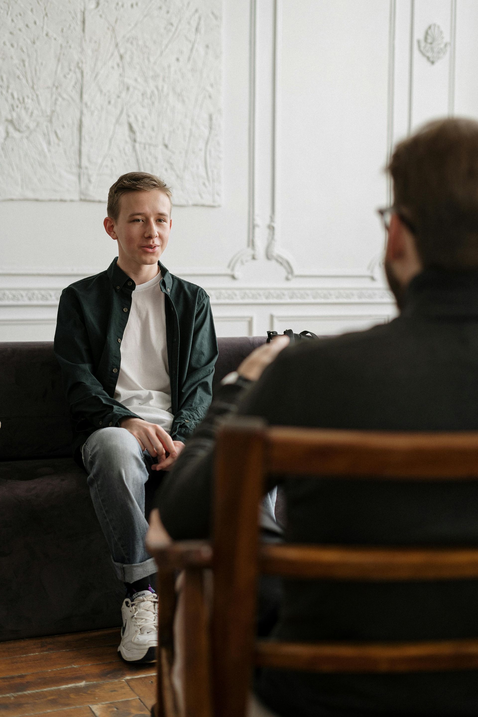 A man and a woman are sitting at a table talking to each other during a counseling appointment.