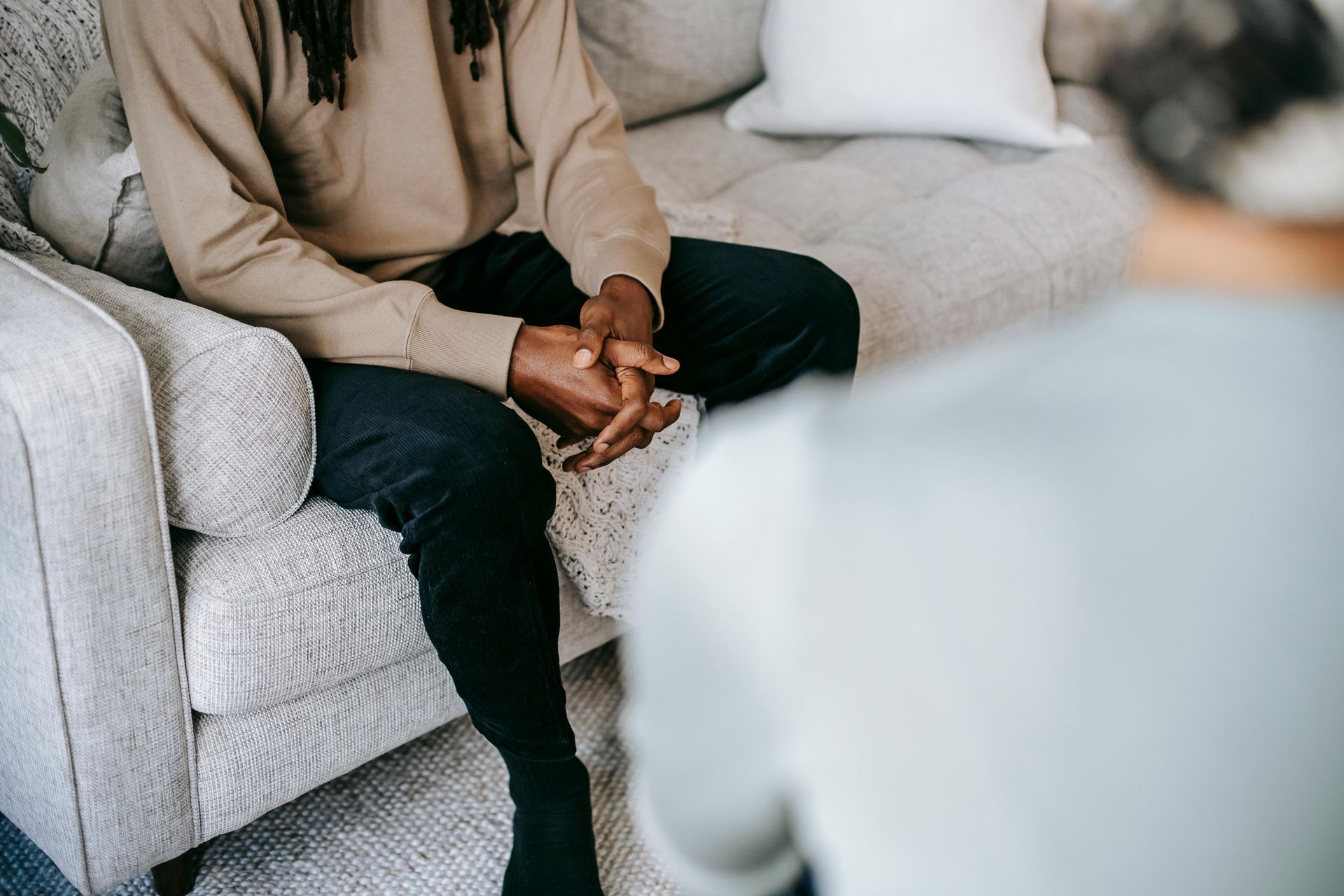 A man is sitting on a couch talking to a woman for counseling.