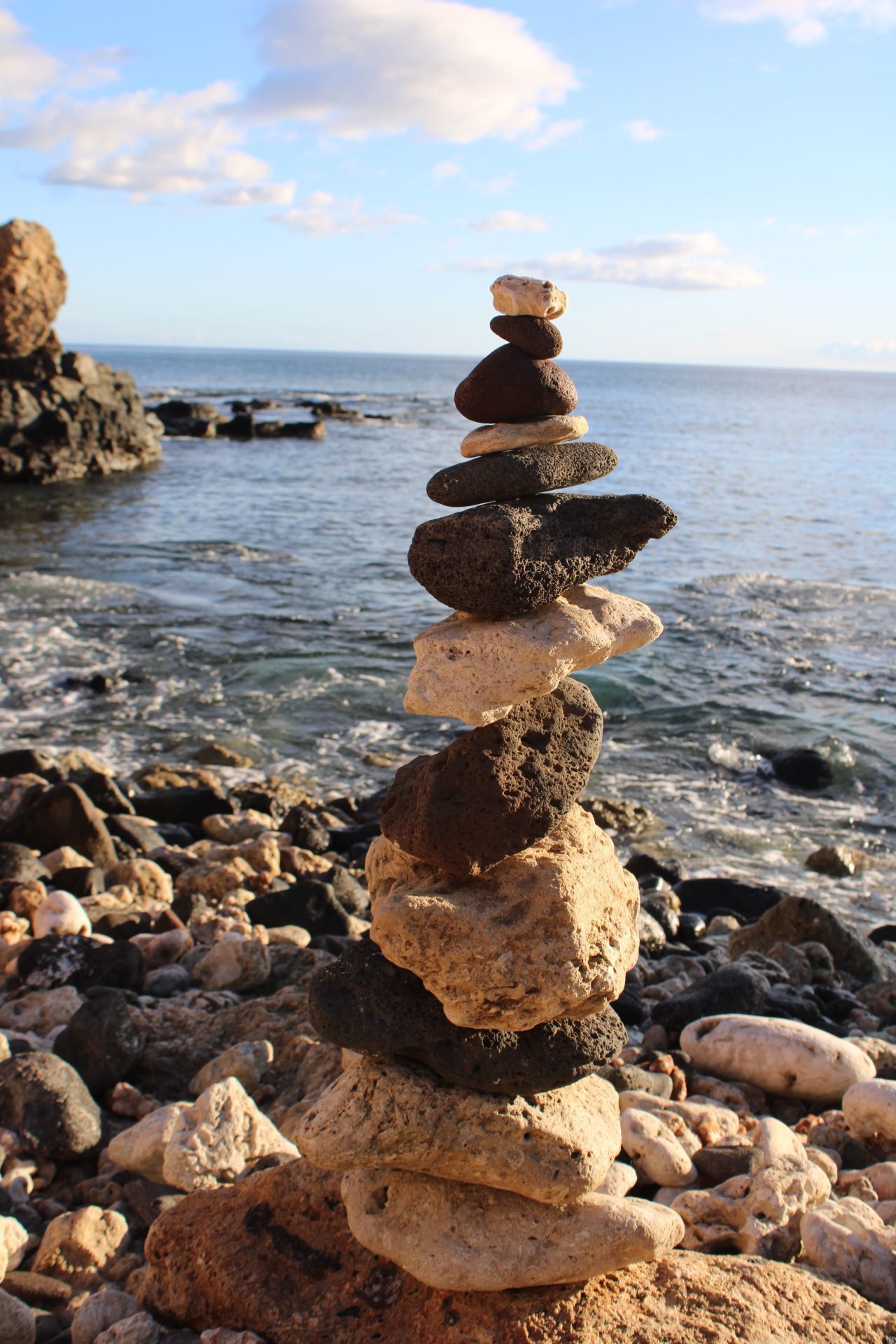 A pile of rocks stacked on top of each other on a beach near the ocean.