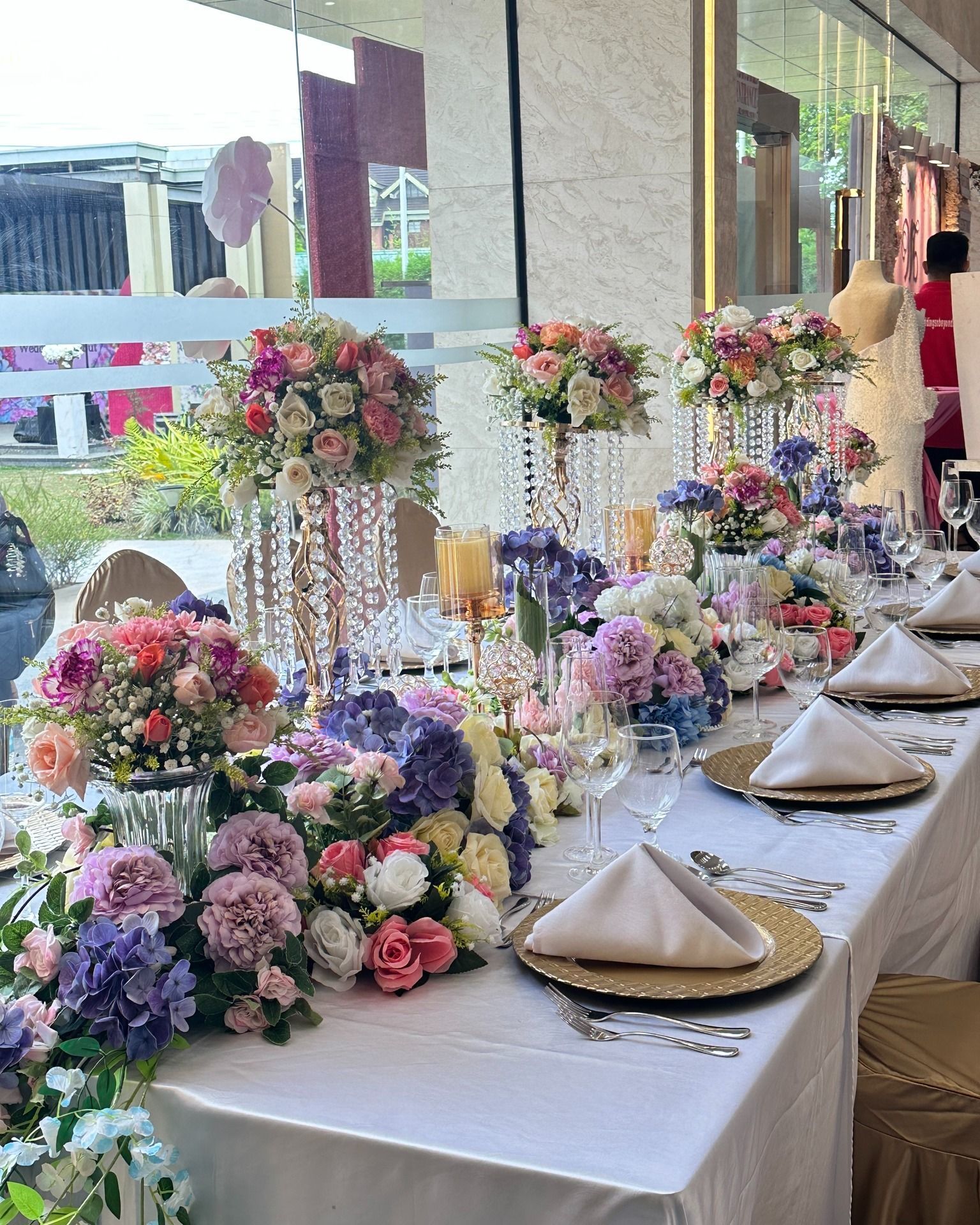 A long table with plates , napkins , candles and flowers on it.