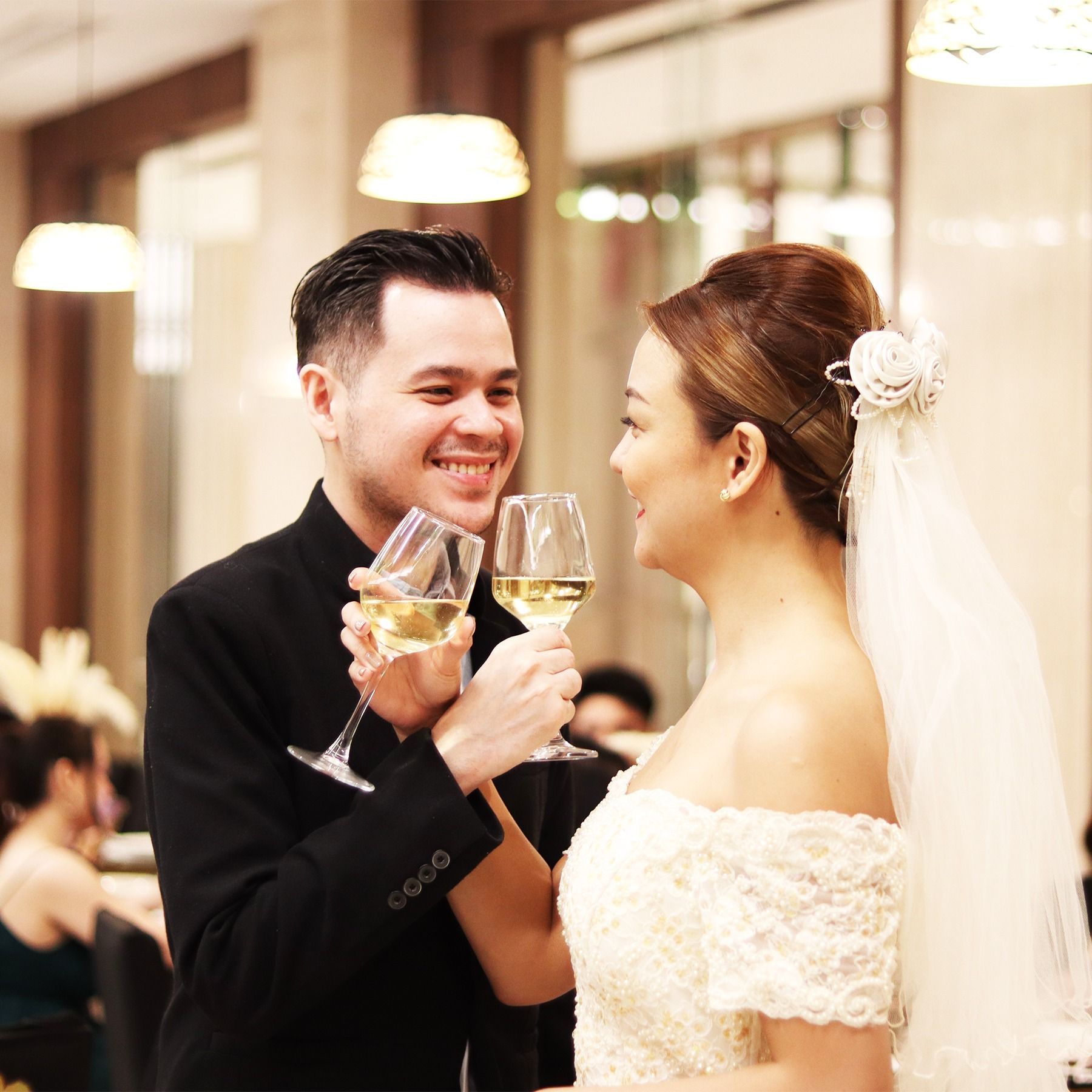 A bride and groom are toasting with wine glasses