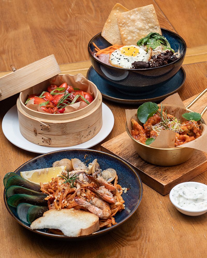 A wooden table topped with plates of food and bowls of food.