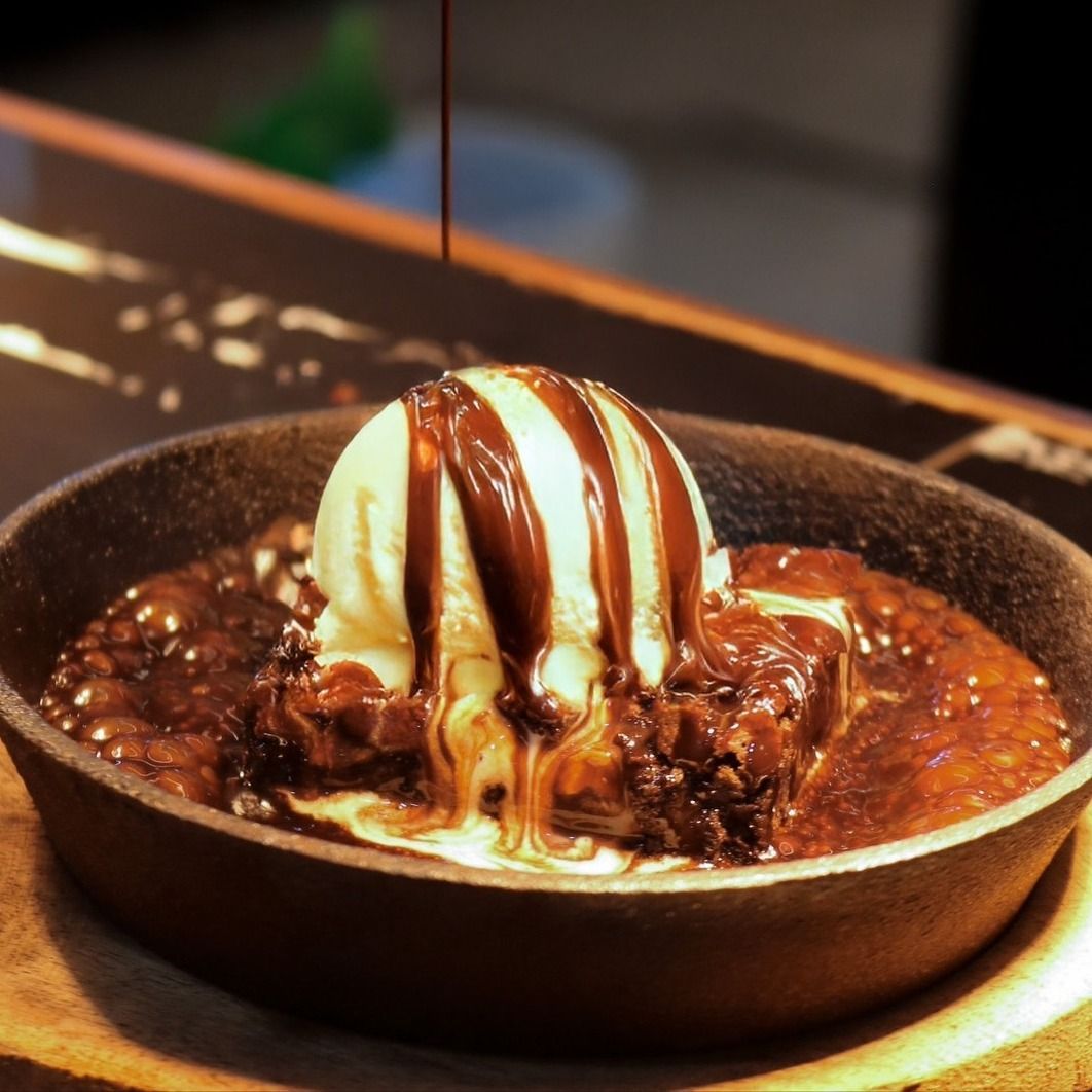 A brownie with ice cream and chocolate sauce on top