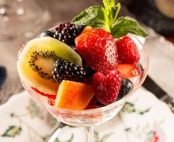 A martini glass filled with fruit and mint leaves