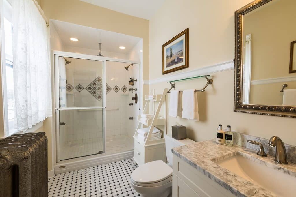 A bathroom with a toilet , sink , shower and mirror.