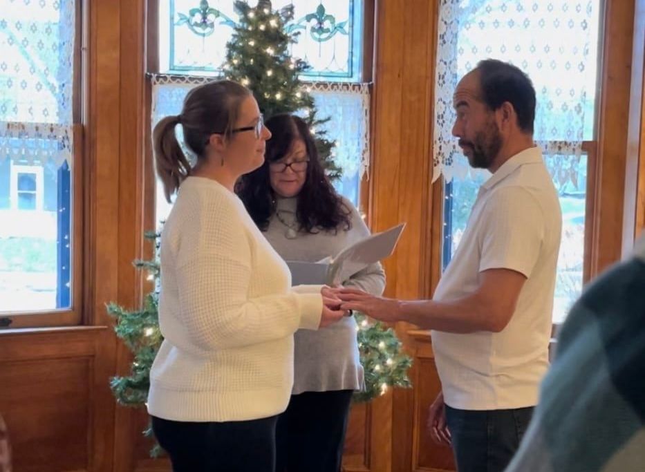 A man and a woman are holding hands in front of a christmas tree.