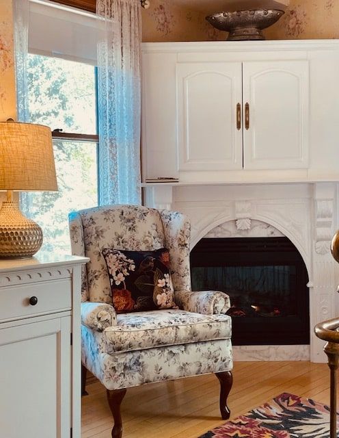 A living room with a chair a lamp and a fireplace