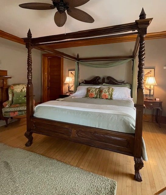 A bedroom with a four poster bed and a ceiling fan