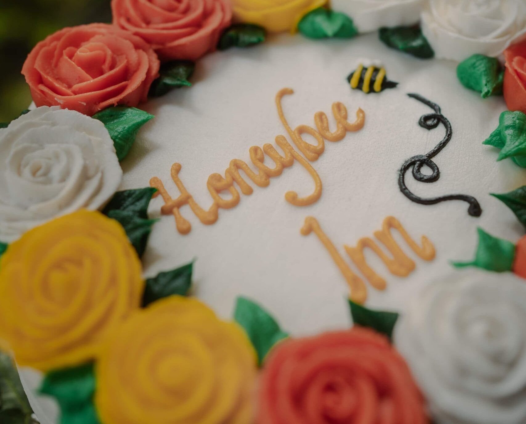 A cake with flowers and the words honeybee inn on it