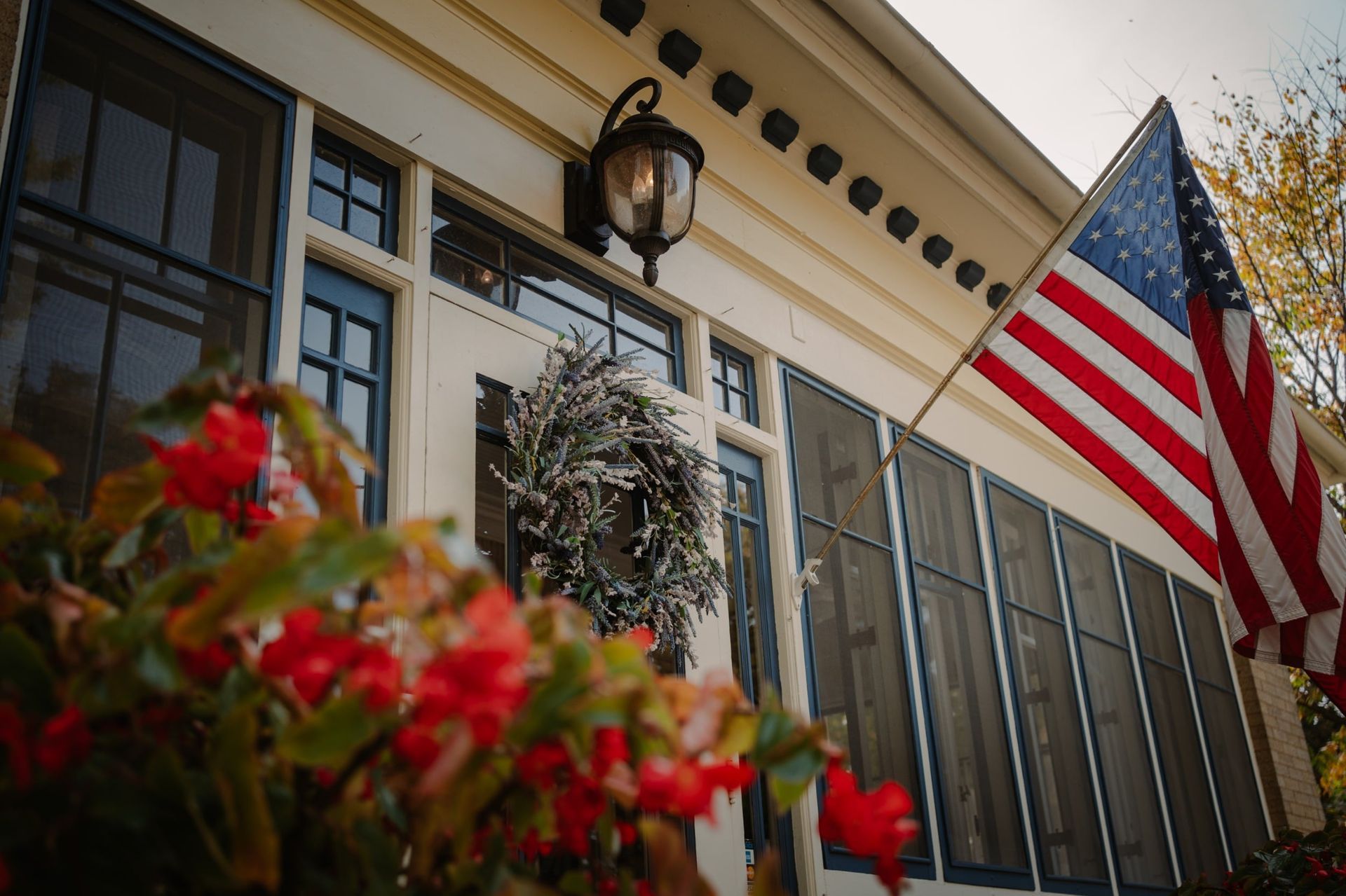 An american flag is hanging from the side of a screened in porch.