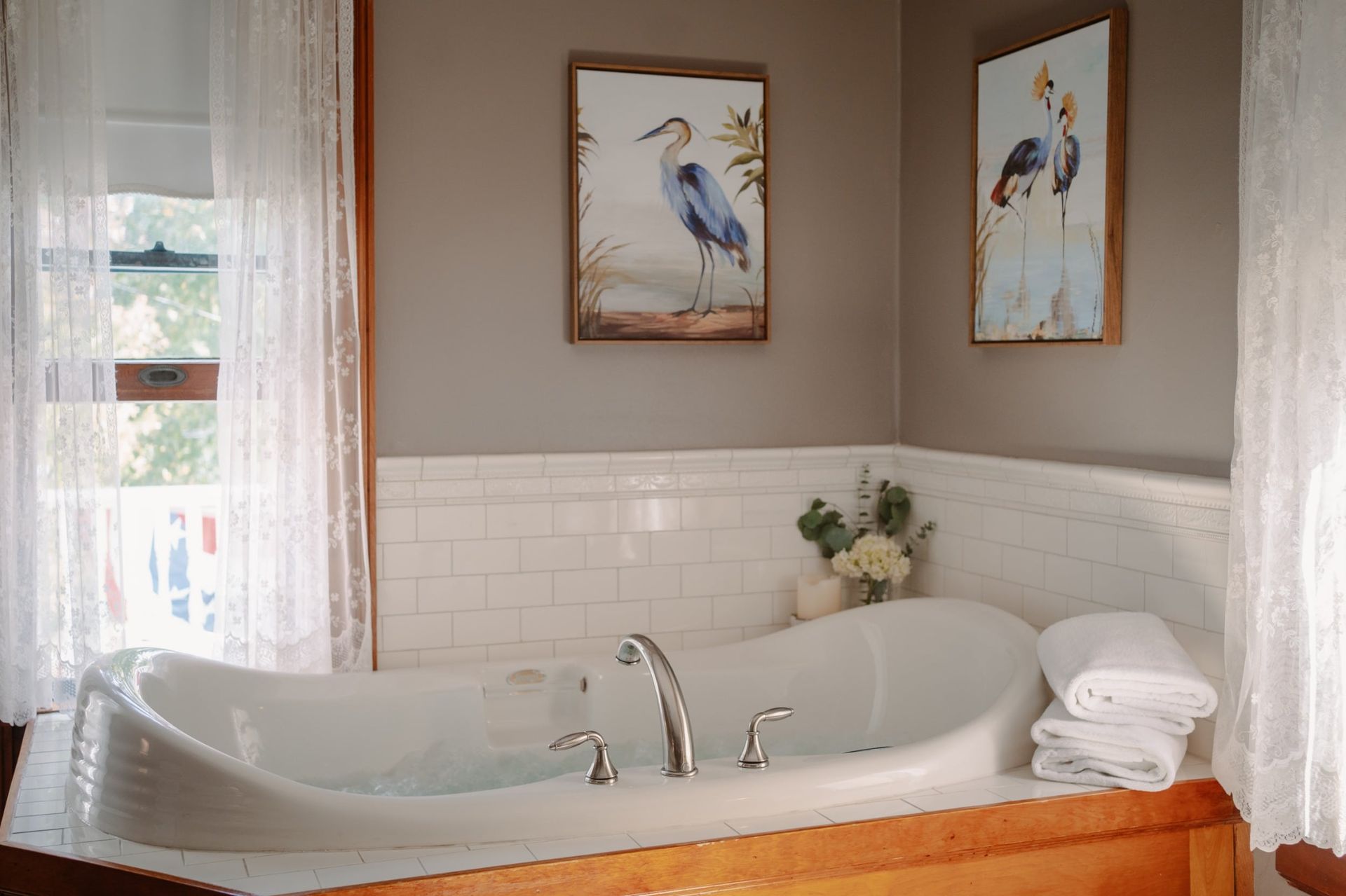 A bathroom with a jacuzzi tub and two paintings on the wall.