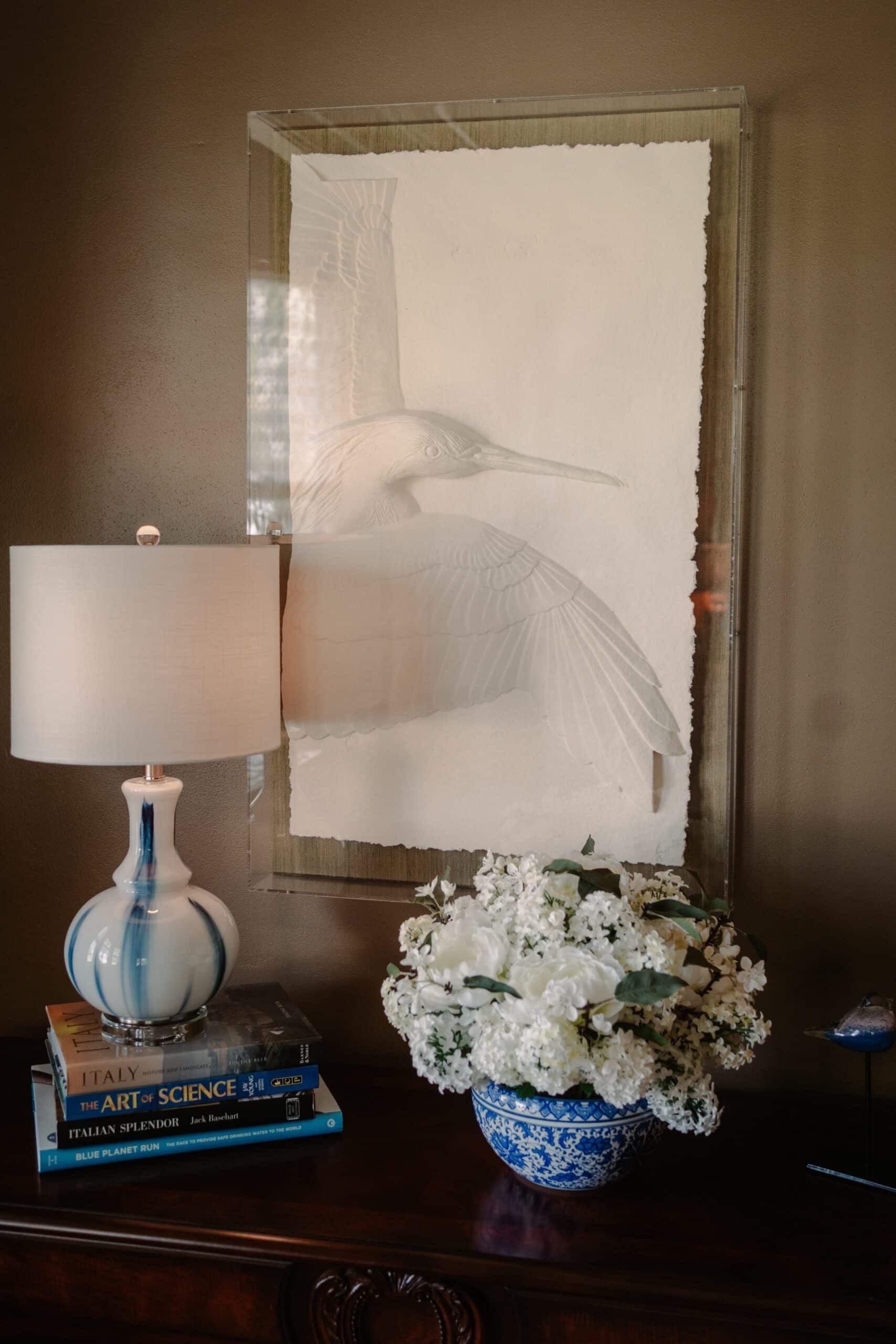 A lamp is sitting on a table next to a vase of flowers.