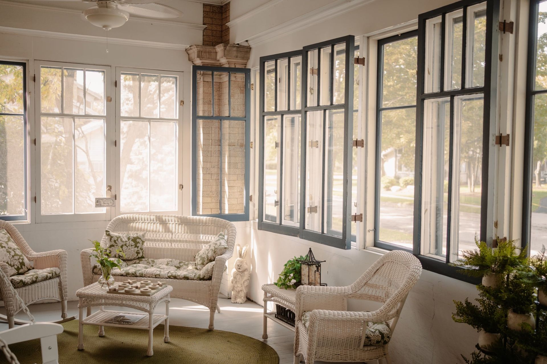 A living room with wicker furniture and lots of windows.
