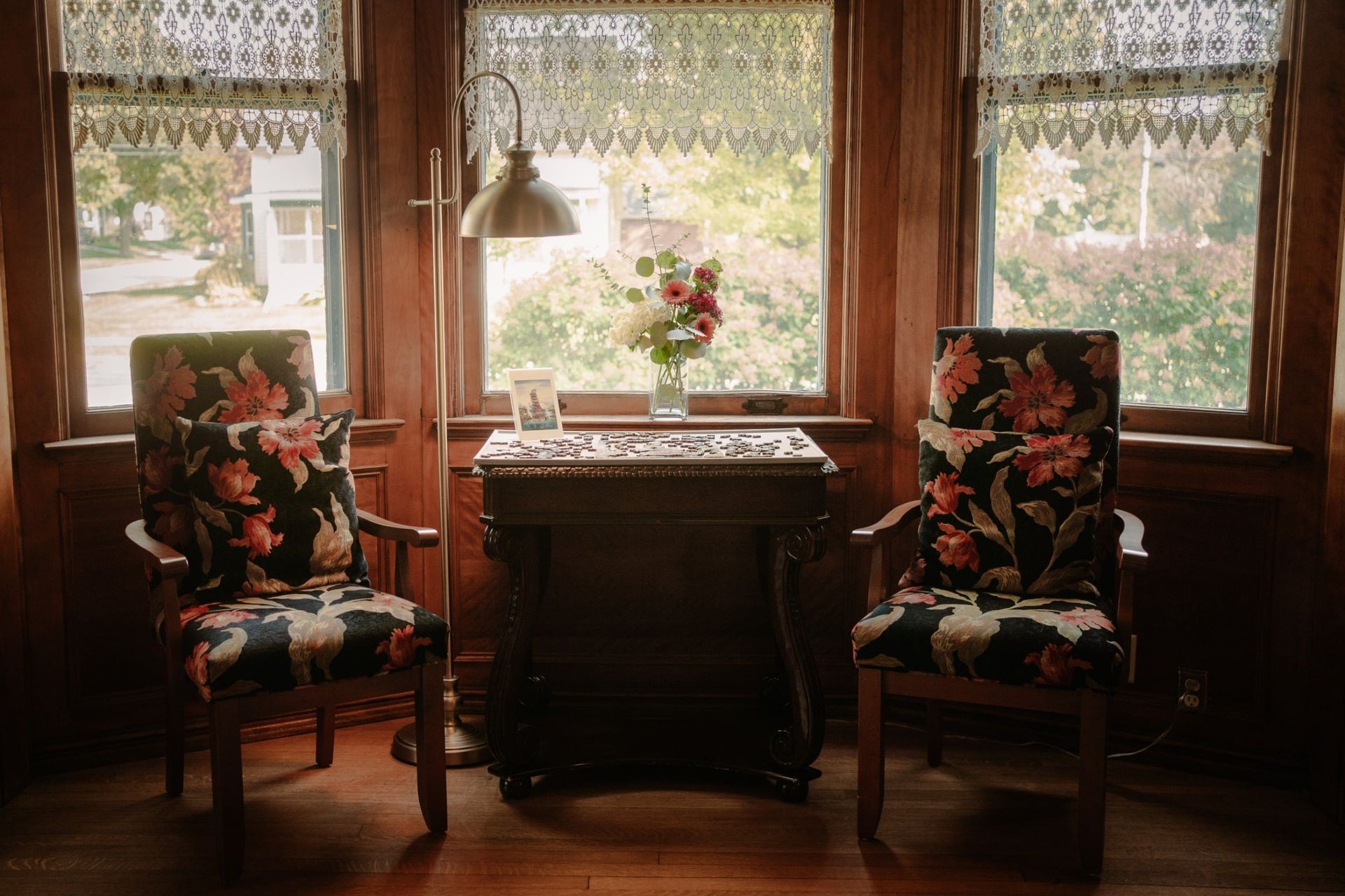 A room with two chairs and a table with a vase of flowers on it.