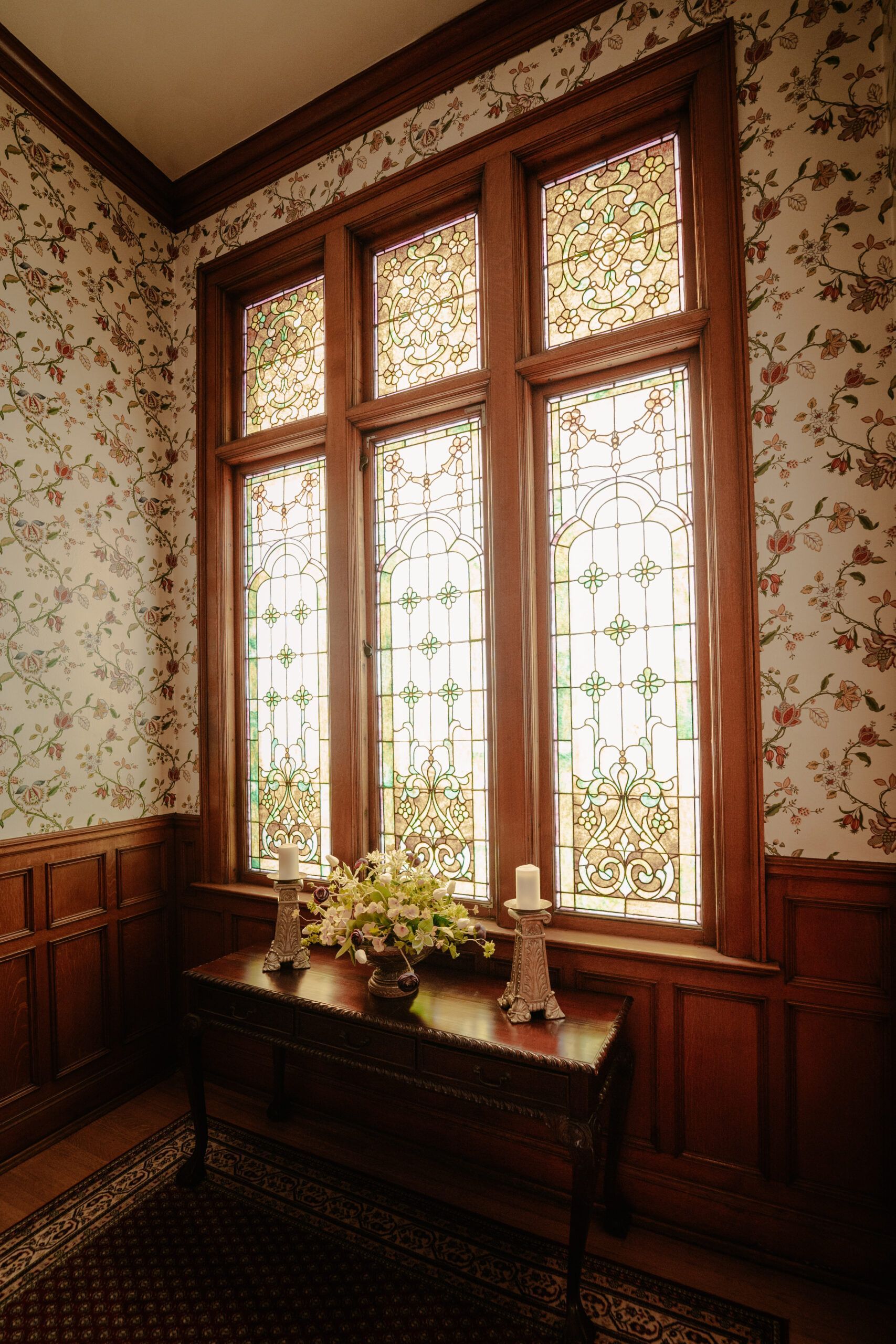 A table with candles on it in front of a window with stained glass