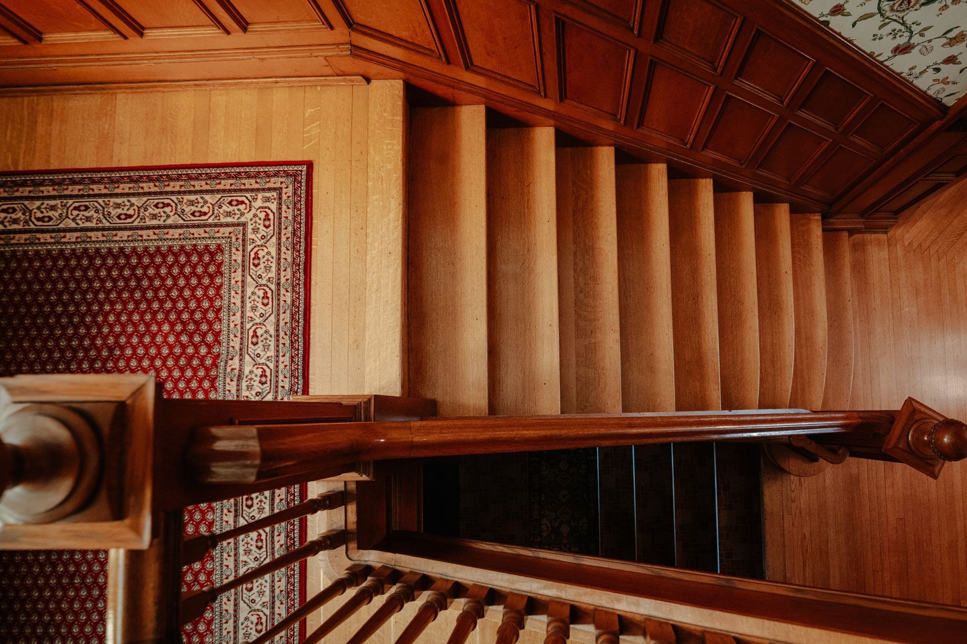 An aerial view of a wooden staircase with a rug on the floor.