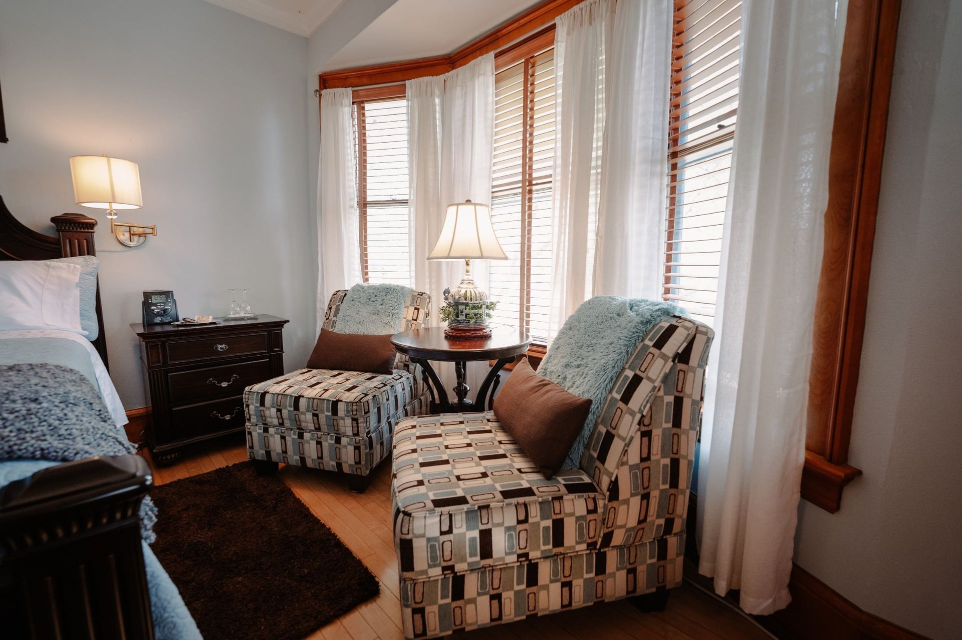 A bedroom with two chairs and a table in front of a window.