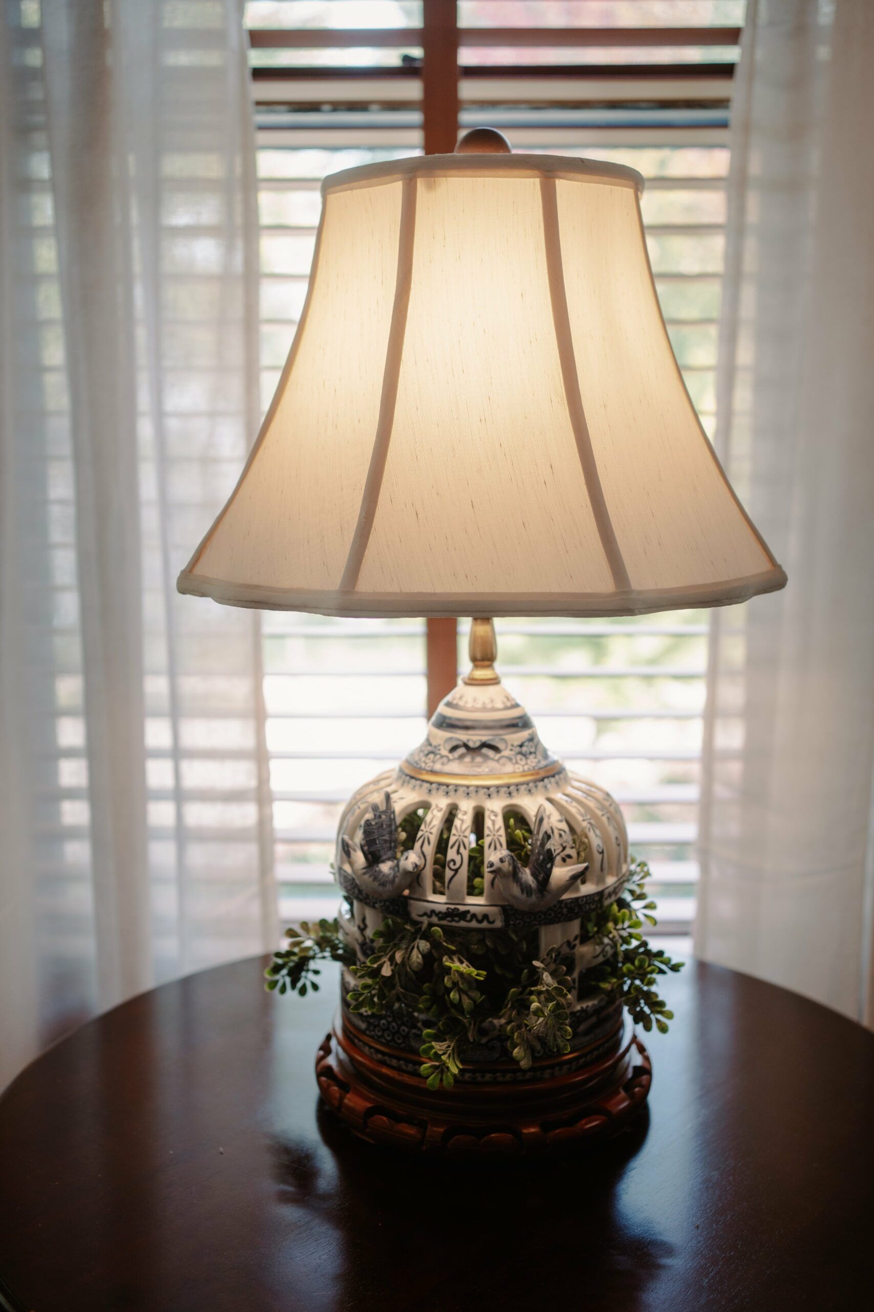 A lamp is sitting on a table in front of a window.