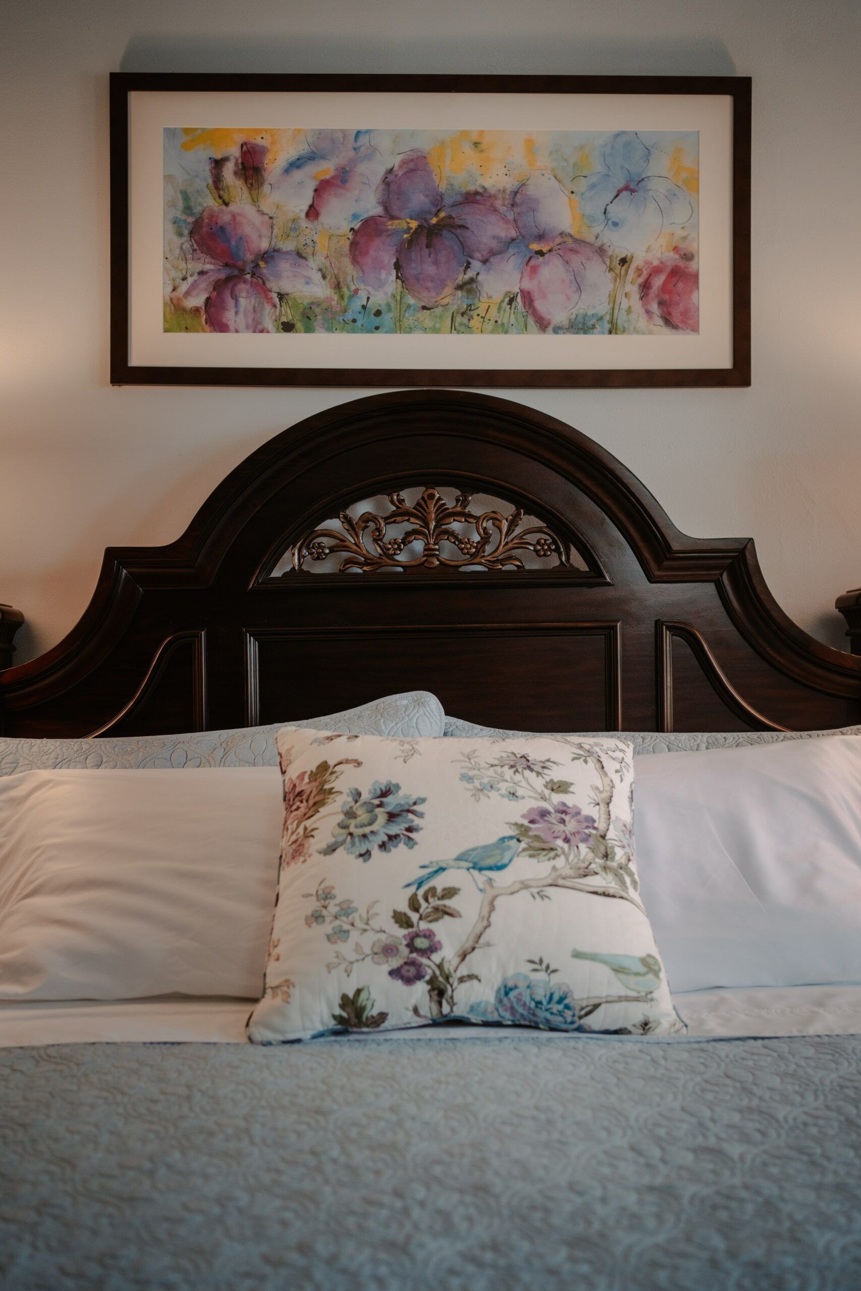 A bed with two pillows and a painting on the wall above it.