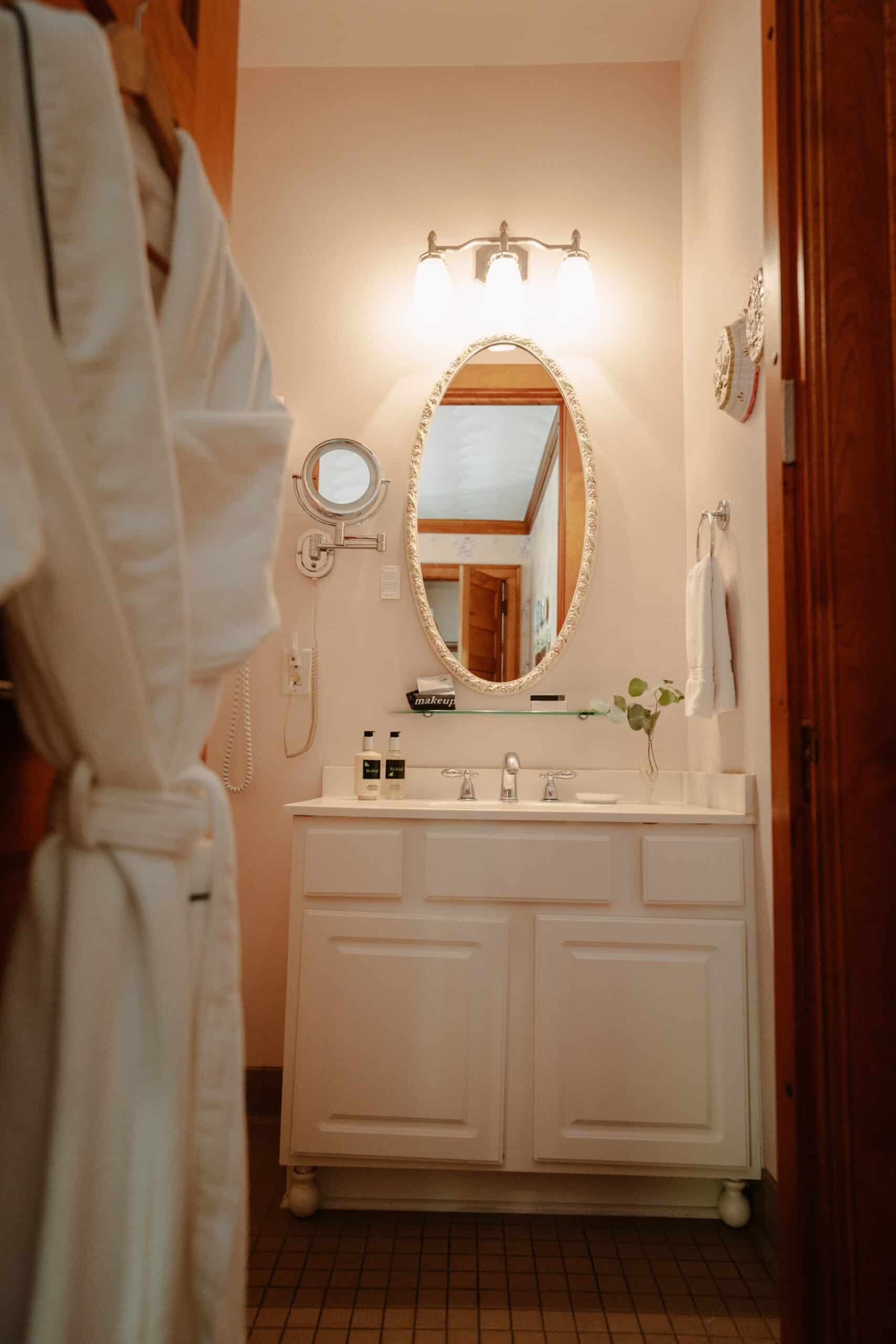 A bathroom with a sink , mirror , and robe.