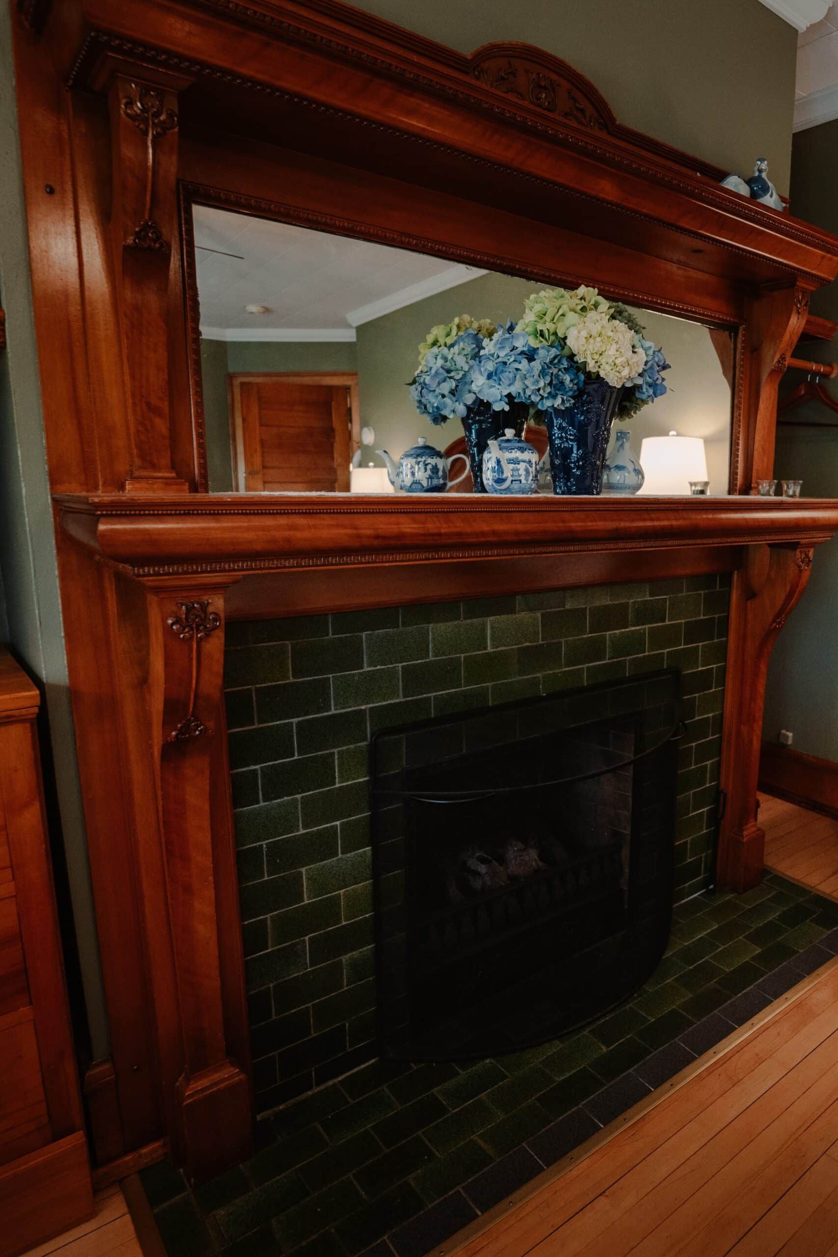 A fireplace with green tiles and a wooden mantle in a living room.