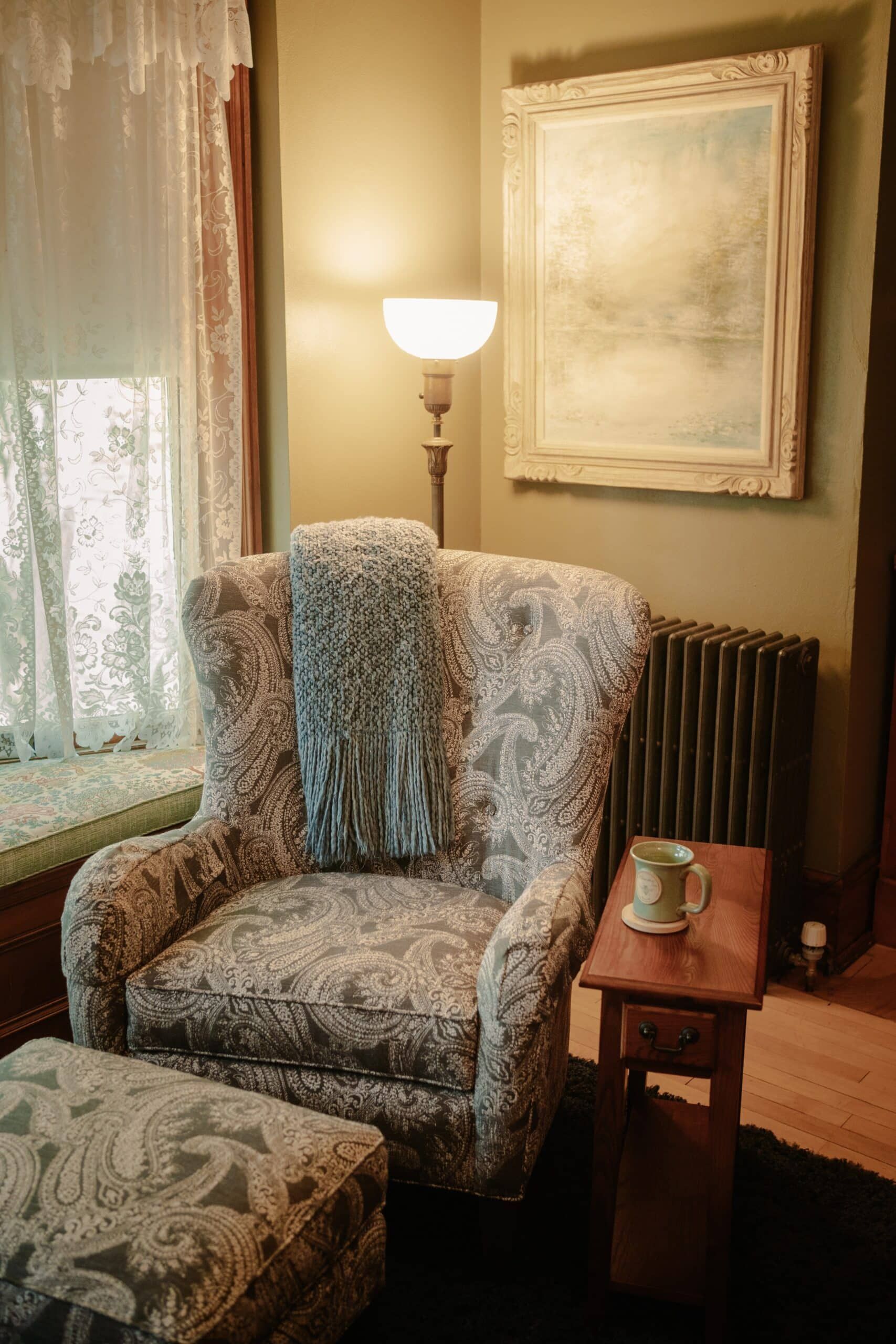 There is a chair and ottoman in the corner of the room.