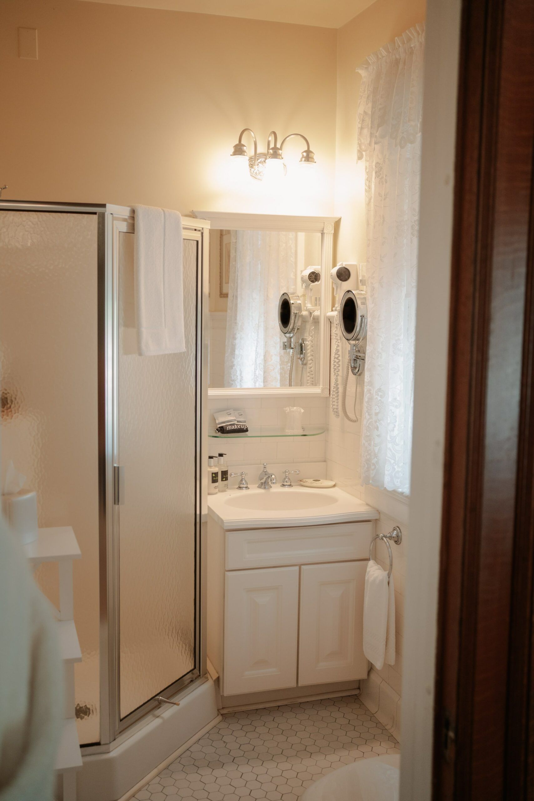 A bathroom with a sink , mirror , and shower stall.