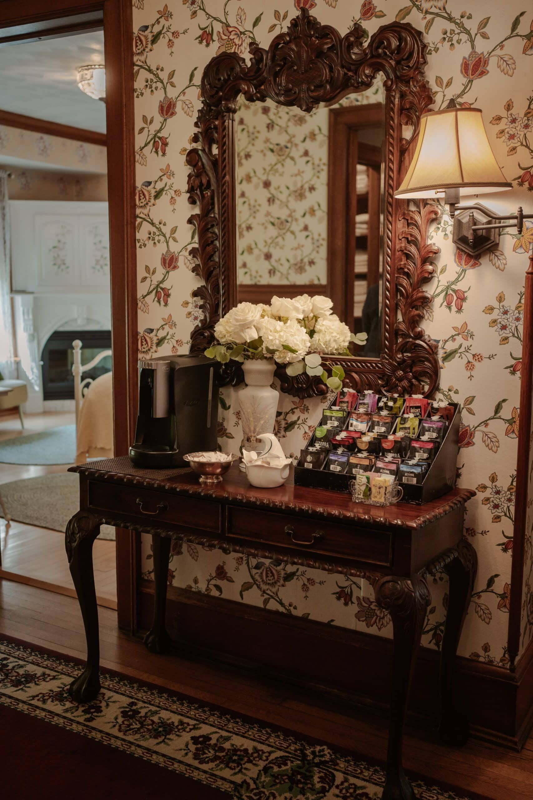 A table with a mirror and flowers on it in a hallway.