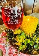 A wine glass is sitting on top of a table next to a candle.