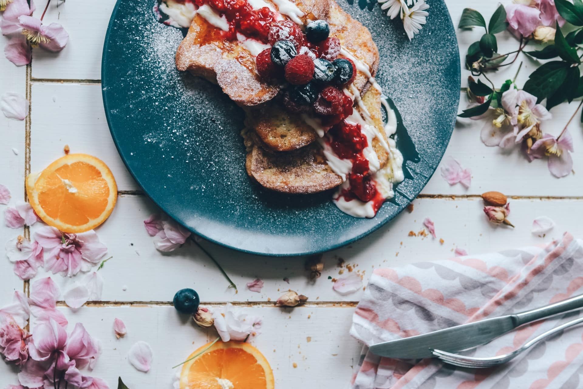 A plate of food with berries and whipped cream on a table.