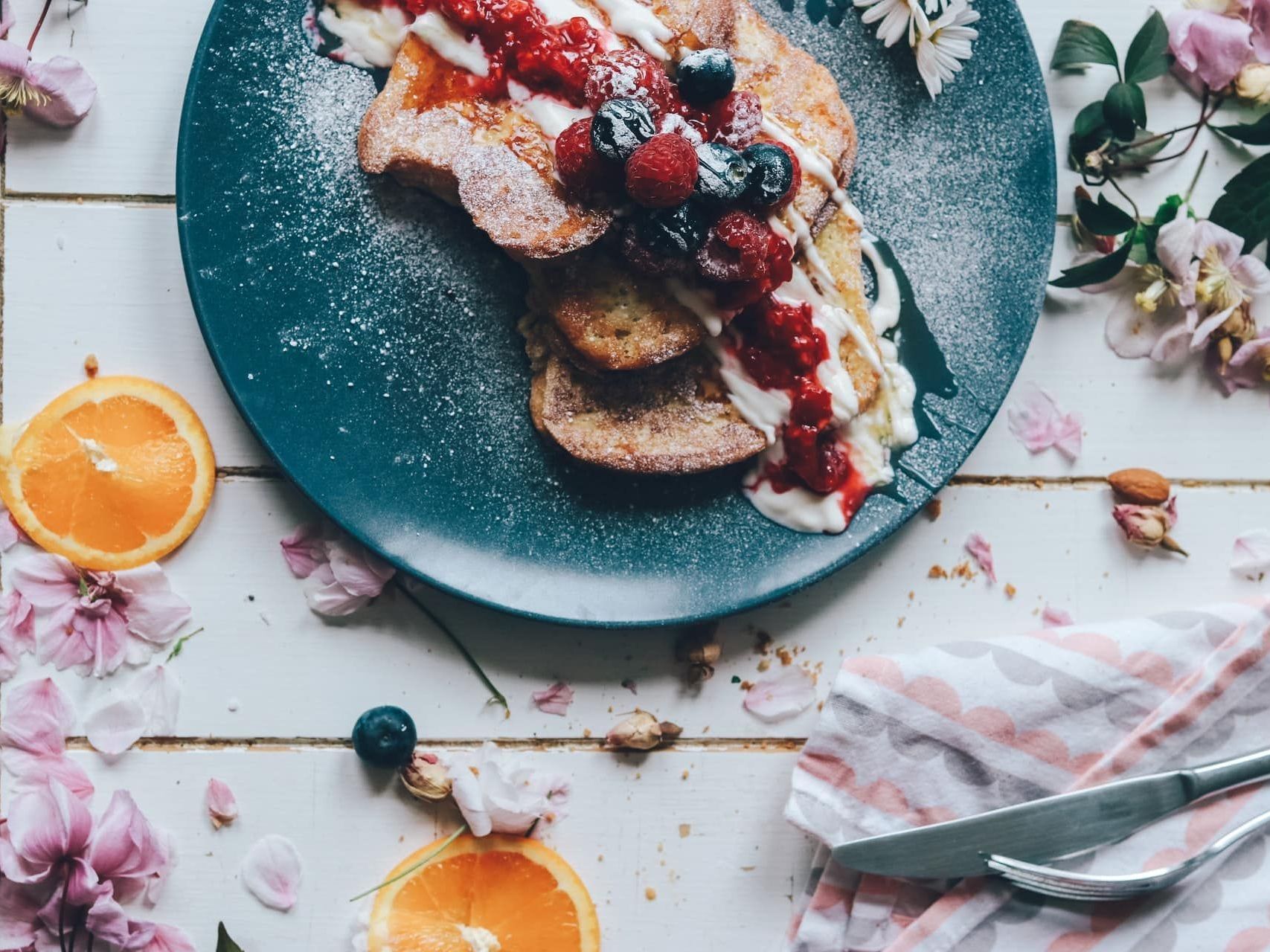 A blue plate topped with french toast and berries on a table.