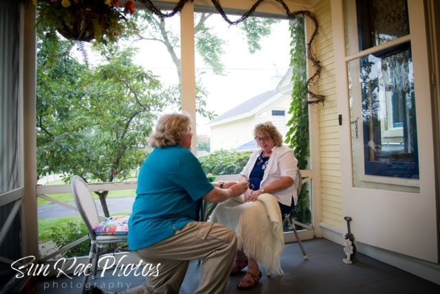 A man and woman are sitting on a porch holding hands