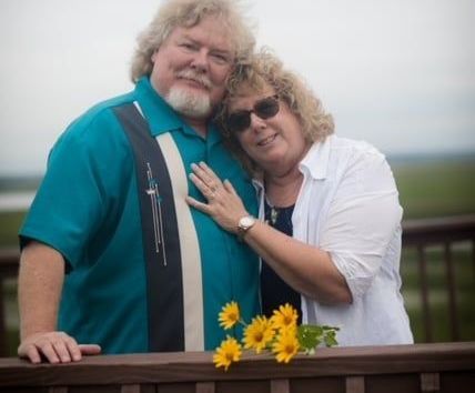 A man and a woman are posing for a picture on a balcony