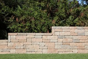 A stone wall is sitting in the middle of a lush green field.