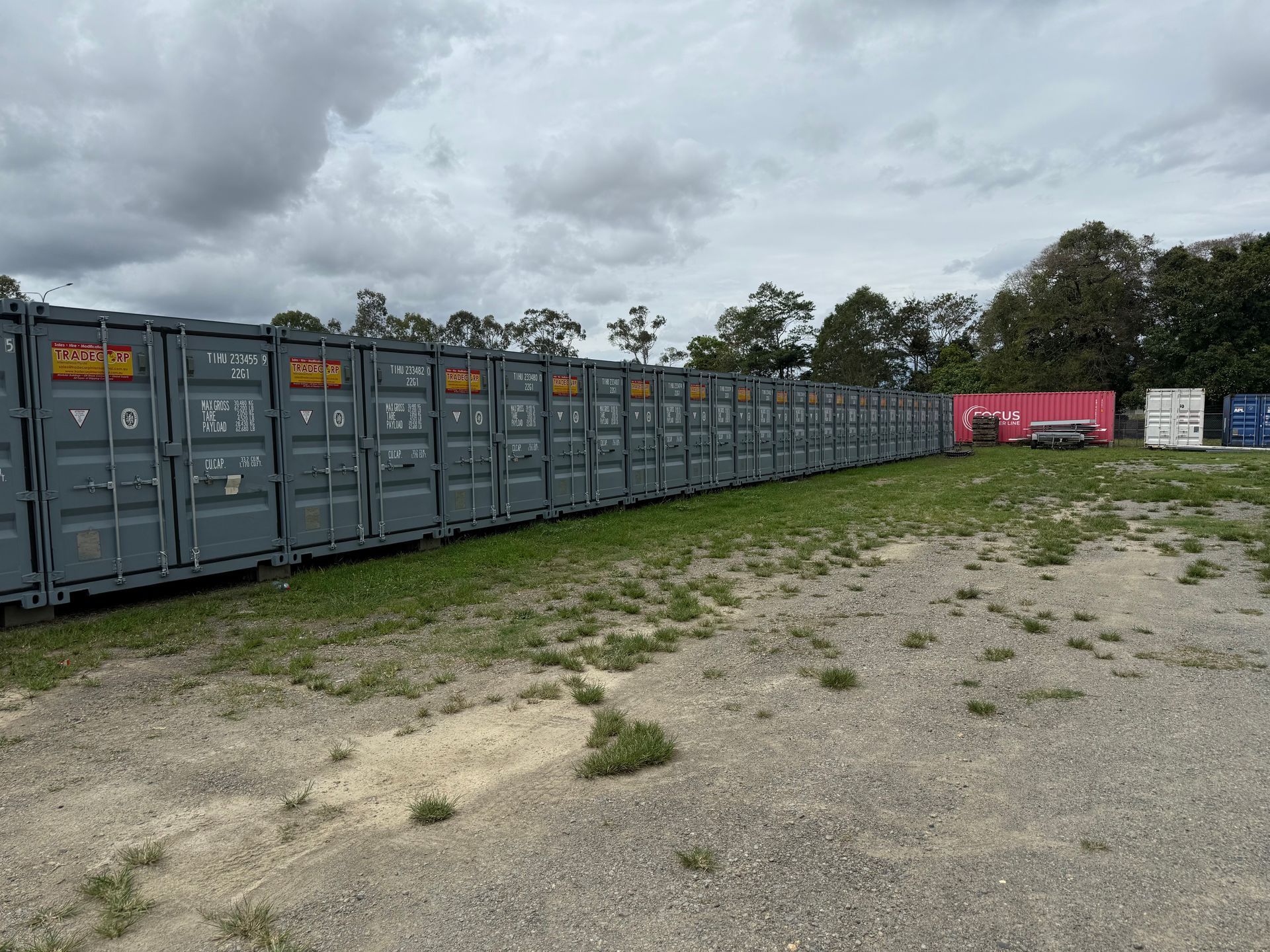 Black caravan parked next to a beige shipping container in an outdoor storage area — Cairns Budget Storage In Mount Sheridan, QLD