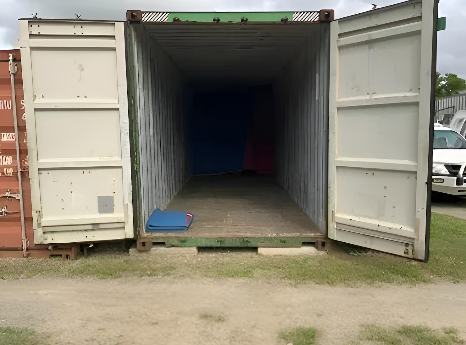Open shipping container, interior empty, blue and pink items at back, doors open, outdoors — Cairns Budget Storage In Mount Sheridan, QLD