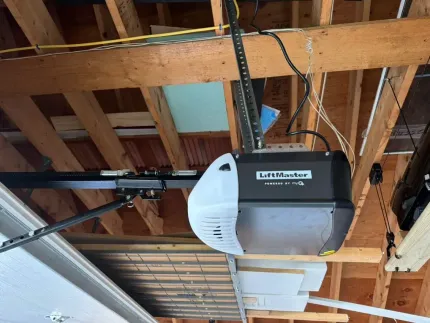 A garage door opener is hanging from the ceiling of a building under construction.